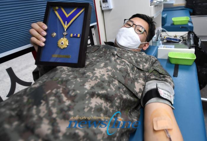 해군 교육사령부 리더십센터 이현종 중사가 2020년 8월 수상한 명예장을 들고 115번째 헌혈을 기념하며 사진 촬영하고 있다
